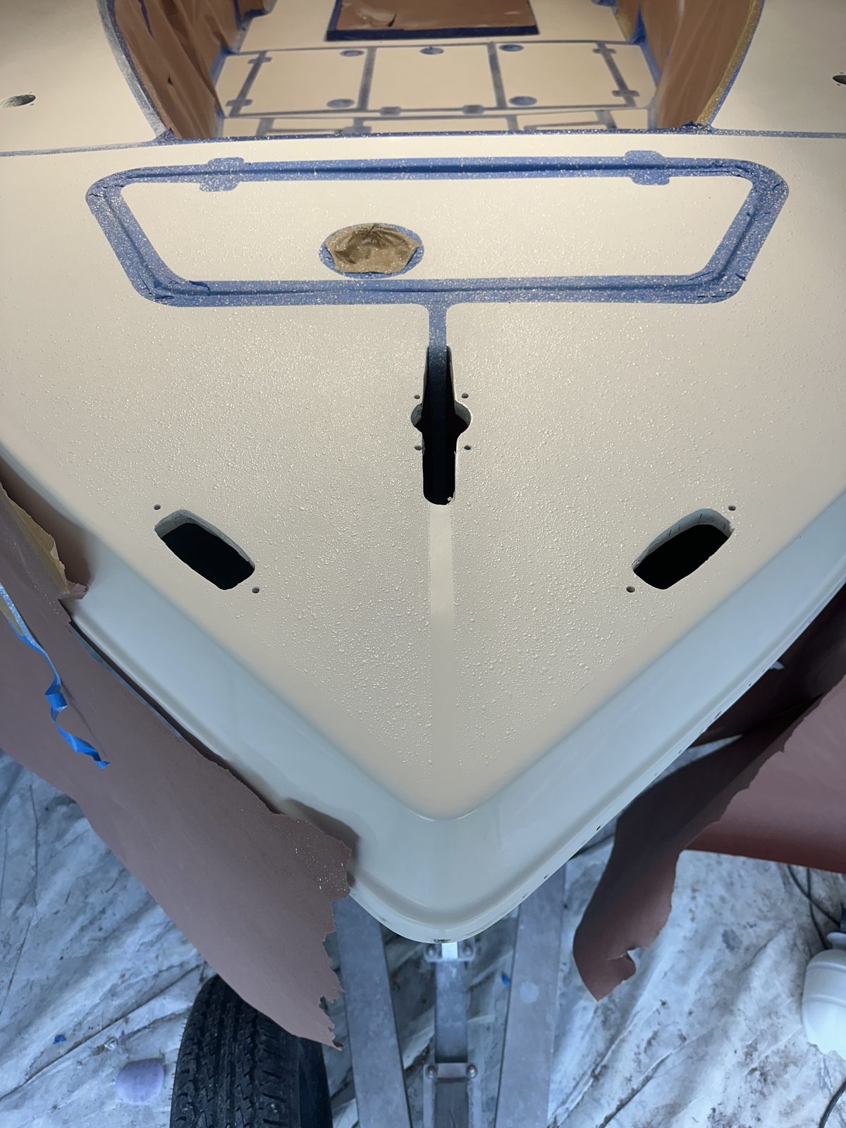 Boat bow deck with fresh non-skid texture, taped off for finishing